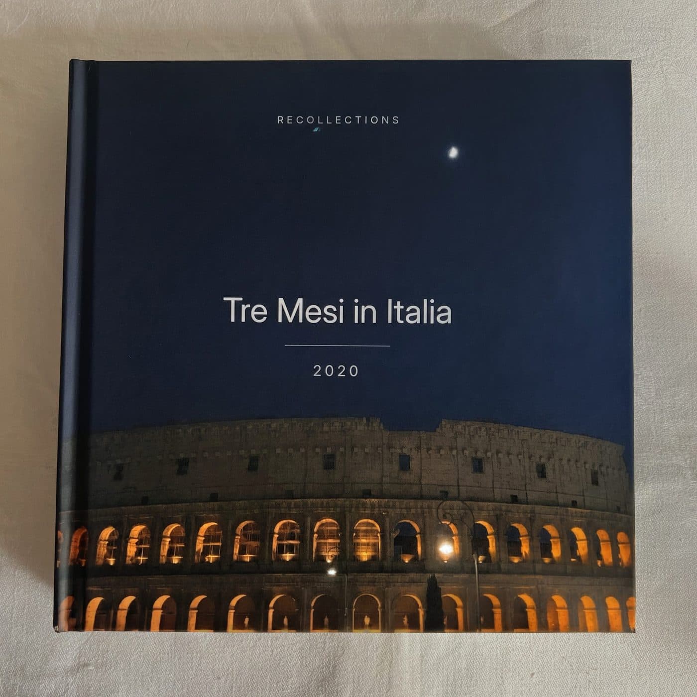 A casewrap hardcover photo book titled Tre Mesi in Italia, the Colosseum lit at night on its cover